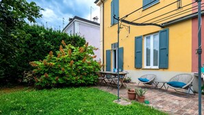 A patio area with a table and chairs, a potted plant, and a hedge. - Wonderful villa, divided over two floors, with garden. Independent entrance.Basement with laundry area.It comfortably accommodates 6 guests in 100 m2 of space with three bedrooms and two bathrooms.LIVING AREA: living room with double sofa bed, 32 TV, si (Parma)