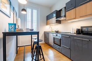 Eine moderne Küche mit Kochinsel, Edelstahlgeräten und einem Fenster, das für natürliches Licht sorgt.