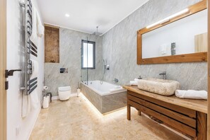 Une salle de bain moderne avec une baignoire, un meuble-lavabo en bois et un grand miroir.