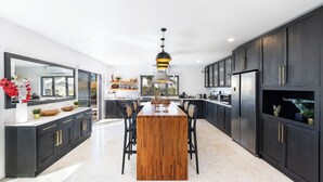 A modern kitchen with dark cabinetry, a wooden island, and a central pendant light. - Stunning!! - Casa Chameleon - Sleeps 14 - Close to Quinta Do Lago & Vale Do Lobo (Faro)