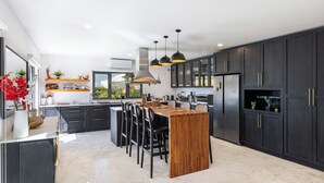 A modern kitchen with dark cabinets, a wooden island, and pendant lighting. - Stunning!! - Casa Chameleon - Sleeps 14 - Close to Quinta Do Lago & Vale Do Lobo (Faro)