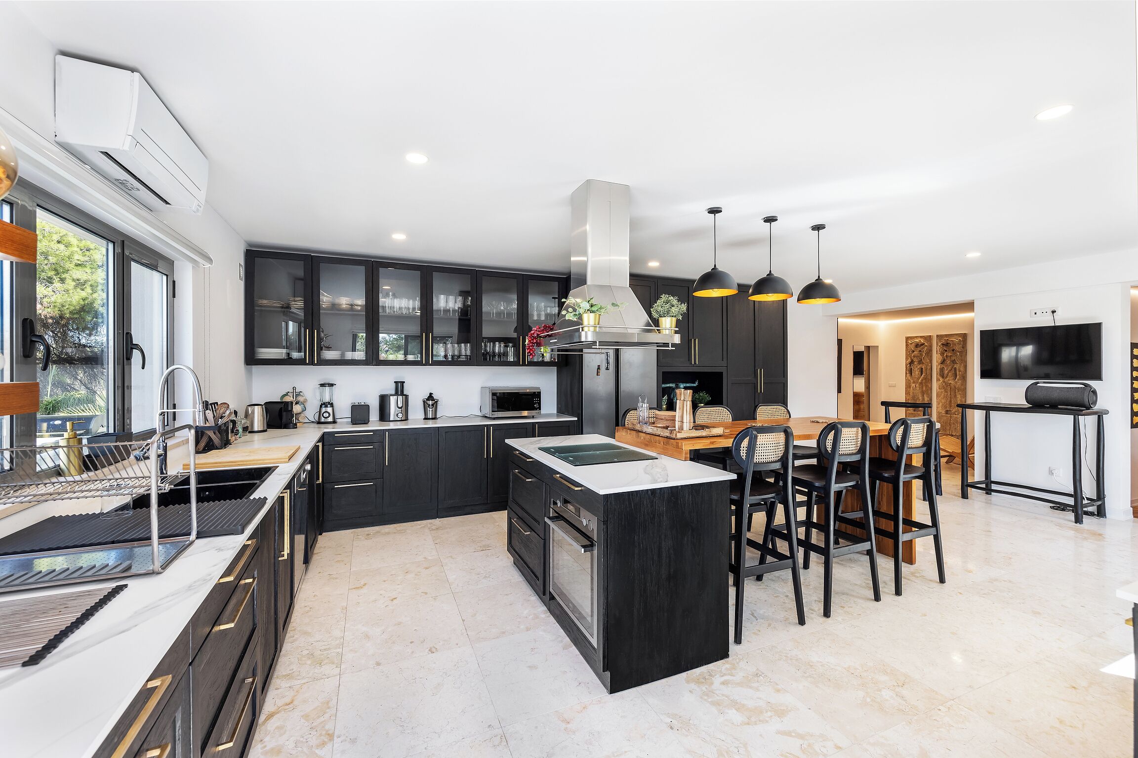 A modern kitchen with dark cabinetry, a central island, and pendant lighting.
