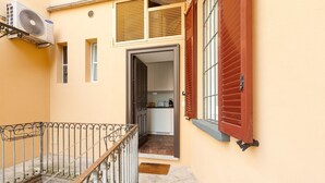 A narrow corridor with a metal railing, a door leading to a kitchen, and a red shutter on the right. - GuestHost - Nice and small Studio-Milan Central Station (Milano)