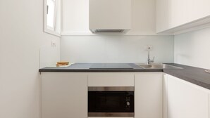 A modern kitchen with white cabinets, a built-in microwave, and a stainless steel sink. - GuestHost - Nice and small Studio-Milan Central Station (Milano)