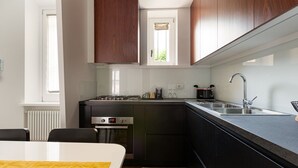 A modern kitchen with dark cabinets, a stainless steel sink, and a window above the countertop. - GuestHost - Modern and comfortable apt - central station! (Milano)