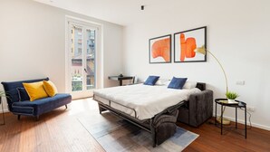 A modern bedroom with a bed, a sofa, a small table, and a potted plant. - GuestHost - Modern and comfortable apt - central station! (Milano)
