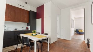 A modern kitchen with dark cabinets, a white island, and a dining area with a white table and chairs. - GuestHost - Modern and comfortable apt - central station! (Milano)