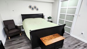 A bedroom with a bed, a chair, a small table, and a sliding door. - Modern Oasis near everything. (Nashville)
