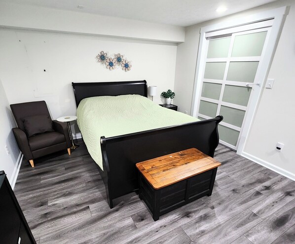 A bedroom with a bed, a chair, a small table, and a sliding door. - Modern Oasis near everything. (Nashville)