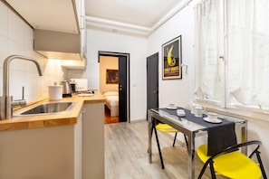 A compact kitchen with a sink, a coffee maker, and a dining area with a table and chairs.