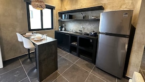 A modern kitchen with a central island, a built-in oven, and a refrigerator. - Coco Live Suites (Playa del Carmen)