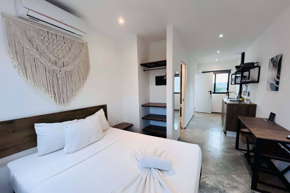 A hotel room with a bed, a desk, and a kitchenette.
