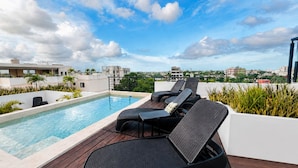 A rooftop pool with lounge chairs and a view of the cityscape. - Coco Live Suites (Playa del Carmen)
