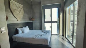 A modern bedroom with a bed, a ceiling fan, and a large window. - Coco Live Suites (Playa del Carmen)