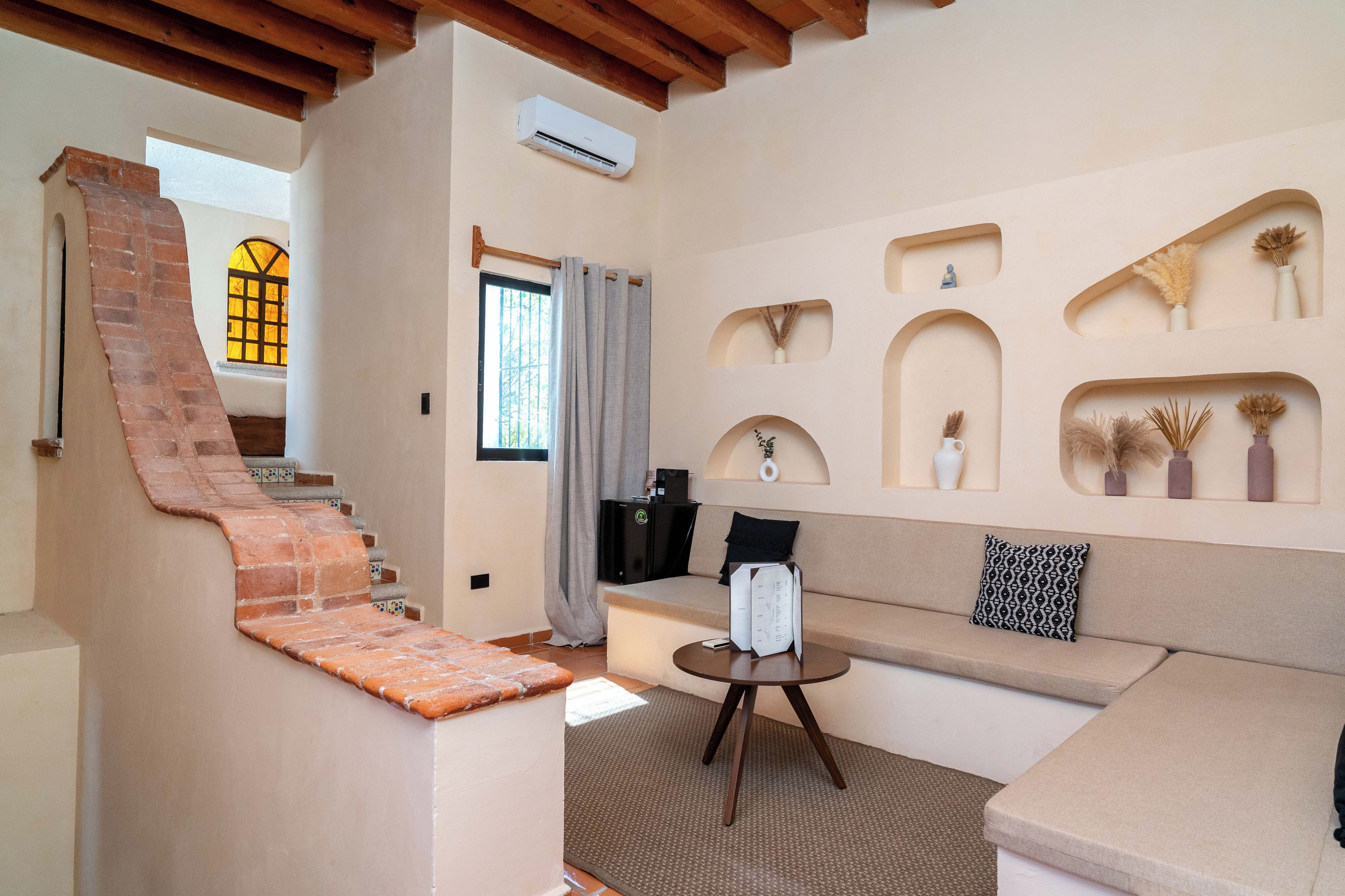 A room with a staircase, a sofa, a small table, and decorative vases.