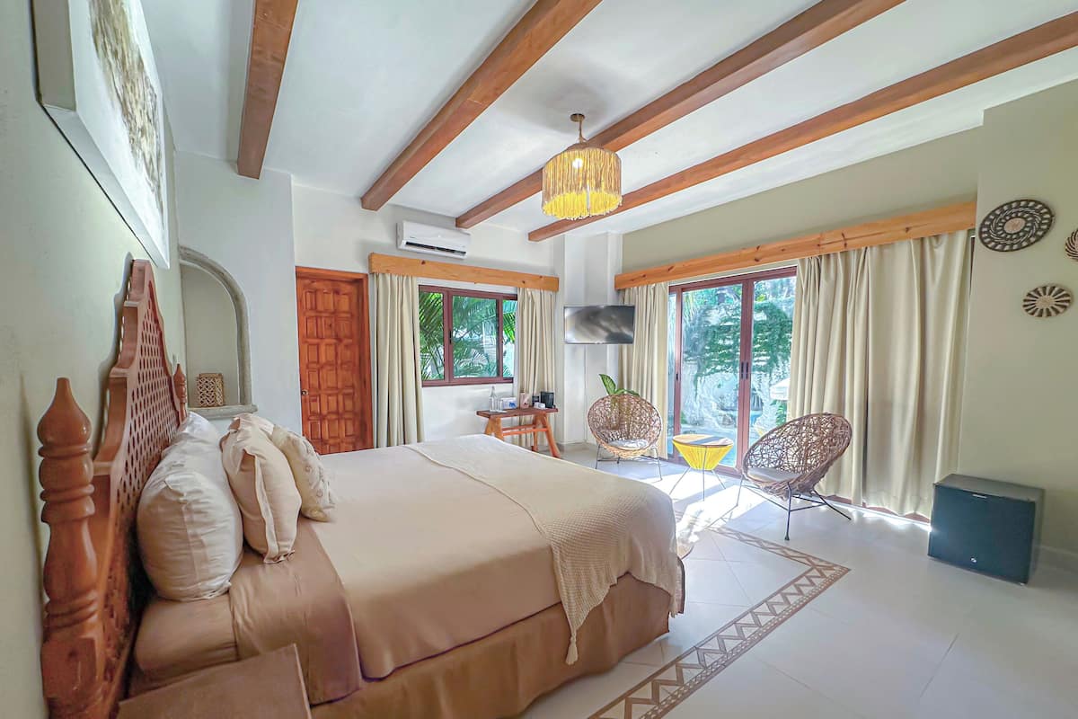 A bedroom with a bed, a TV, a window, and a balcony.