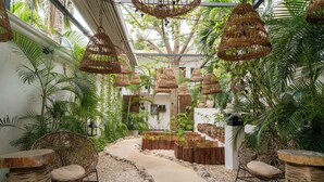 Un jardin tropical agrémenté de meubles en osier, d’un chemin de gravier et de jardinières suspendues.
