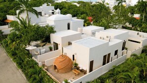 Un immeuble résidentiel moderne composé de plusieurs structures blanches, d’un bâtiment central en forme de dôme et entouré d’une végétation luxuriante.