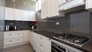 Una cocina moderna con armarios blancos, estufa a gas y horno empotrado.