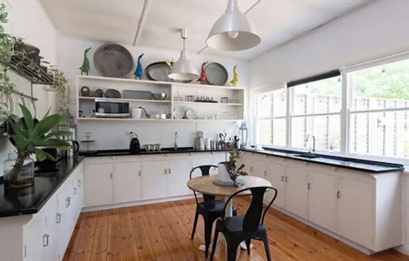 Enjoy meals in this well-equipped kitchen with a dining table and chairs, surrounded by decorative items and natural light.