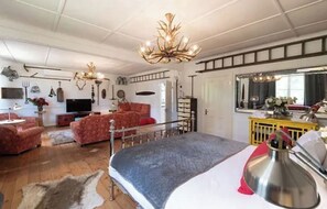Relax in this stylish living area with a large bed, high ceiling, and decorative chandelier.