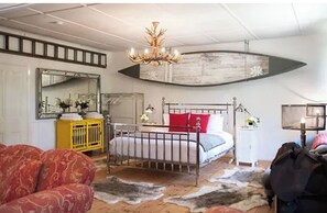 Experience the unique blend of style and comfort in this beautifully designed bedroom, featuring a statement headboard, elegant chandelier, and eclectic decor.