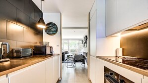 Una cocina moderna con electrodomésticos integrados, un comedor con mesa y sillas, y vistas al exterior.