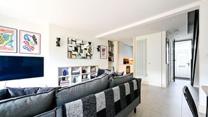 Una sala de estar moderna con un sofá gris, un televisor de pantalla plana y una estantería.