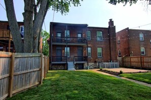 Un bâtiment en briques de deux étages, doté d’une terrasse en bois et d’une cour clôturée.