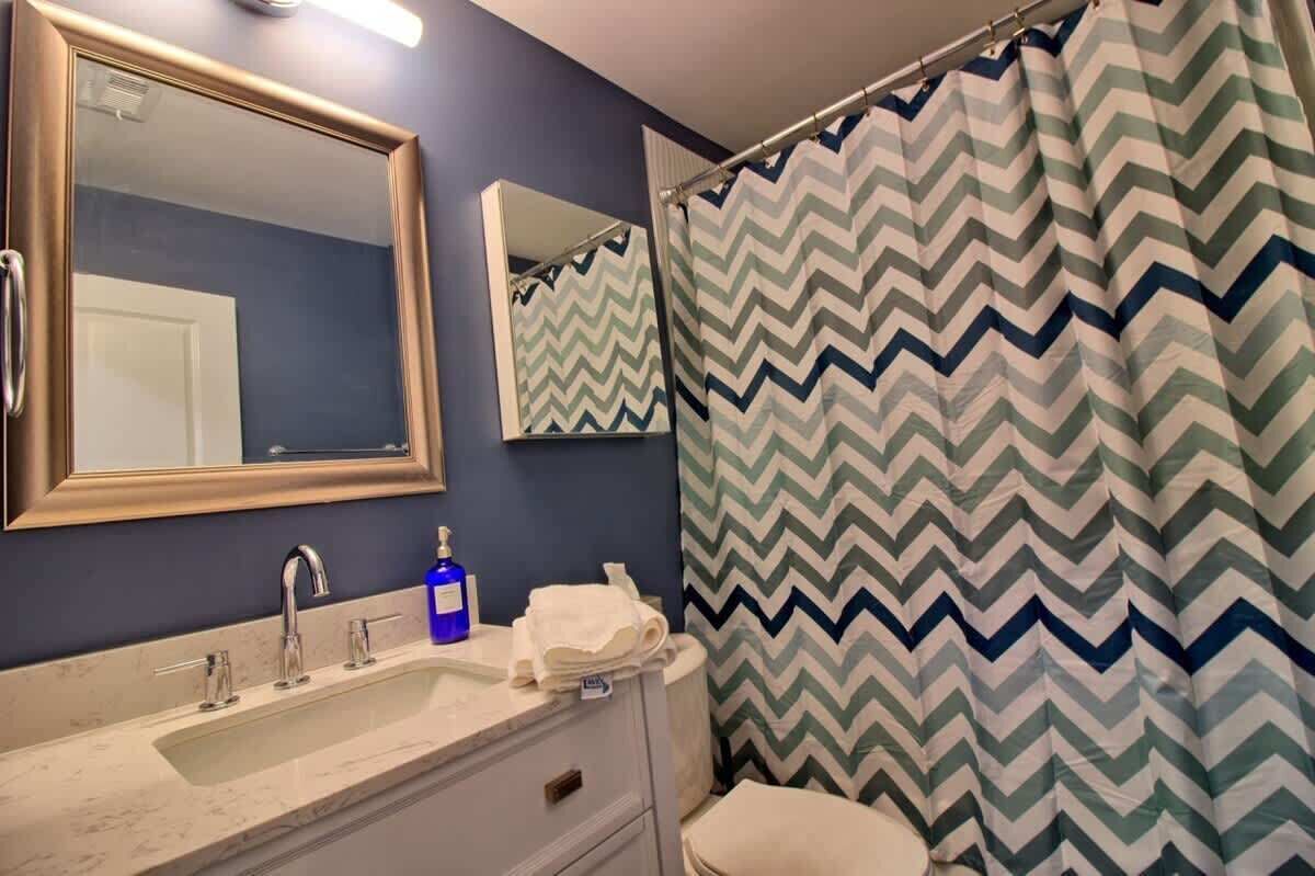 Un bagno con specchio, lavandino e tenda della doccia.