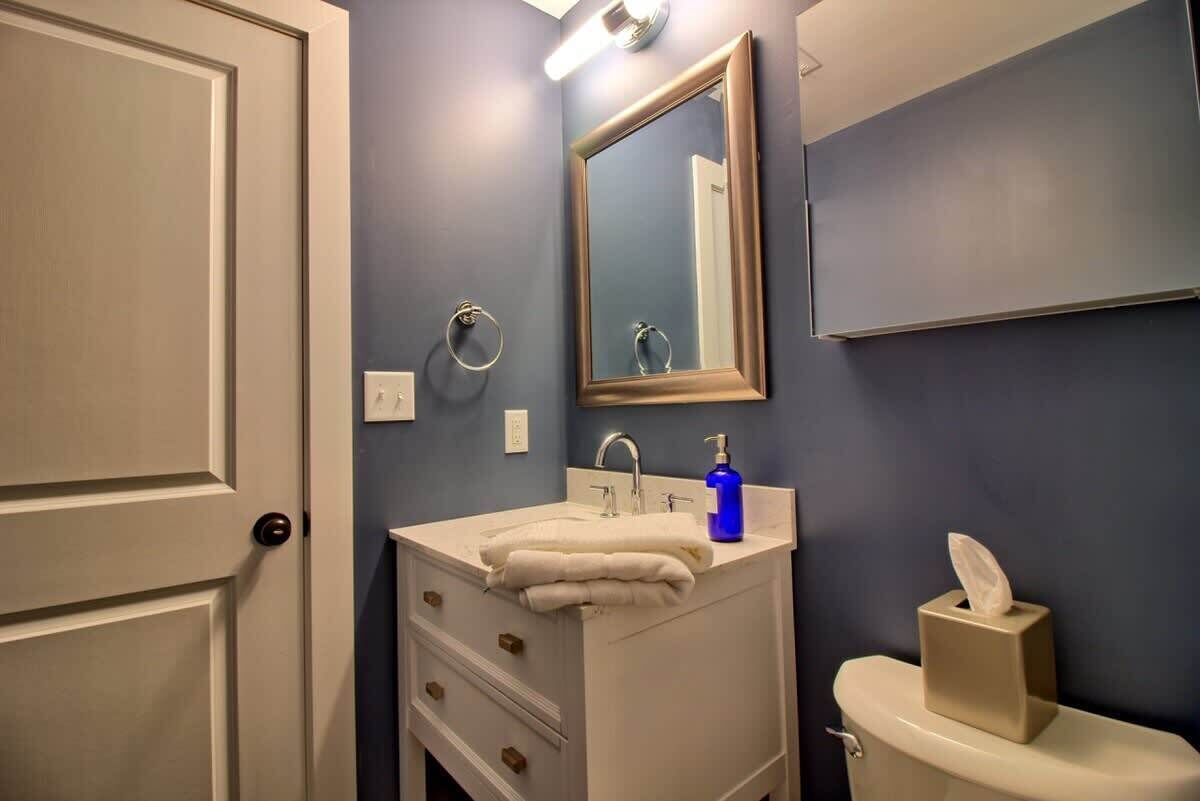 A bathroom with a white sink, mirror, and toilet.
