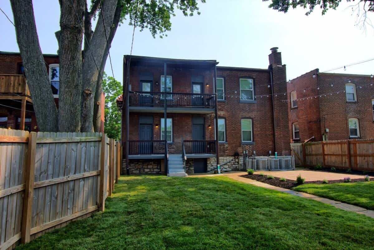 A two-story brick building with a wooden deck and a fenced yard.