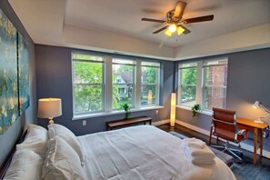 A bedroom with a bed, a desk, a chair, and a ceiling fan.