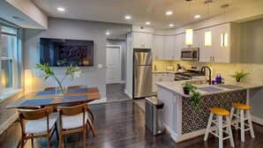 Una cocina moderna con armarios blancos, electrodomésticos de acero inoxidable y una isla central con taburetes.