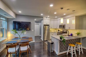 Una cocina moderna con una isla central, electrodomésticos de acero inoxidable e iluminación colgante.