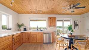 A modern kitchen with wooden cabinets, a dishwasher, and a dining area with a round table and chairs.
