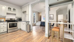 A modern kitchen with white cabinetry, stainless steel appliances, and a wooden floor.