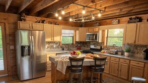 Una cocina con armarios de madera, un refrigerador de acero inoxidable, un microondas y una isla grande con taburetes.