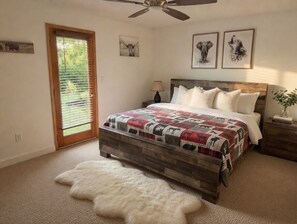 A bedroom with a bed, a wooden headboard, a nightstand, a lamp, and a door with blinds. - Awesome Views, 10 Min To Gatlinburg and Pigeon forge. Wi-Fi, Hot Tub, Grill (Sevierville)