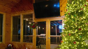 Un acogedor interior de cabaña con paredes de madera, un televisor en la pared y un árbol de Navidad decorado.