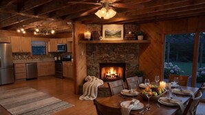 Una cocina acogedora con armarios de madera, una chimenea de piedra y un comedor con mesa para cuatro.