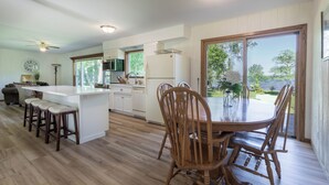 Cocina moderna con una isla central, mesa de comedor de madera y sillas, y vista al exterior.