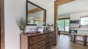 Un aparador de madera con cajones, un espejo grande y un letrero de bienvenida en una habitación con pisos de madera y ventanas amplias.