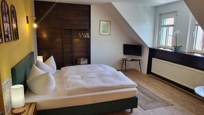 A bedroom with a bed, a TV, a window with a view, and a wooden wardrobe. - Pension Zur Neuenburg (Freyburg)