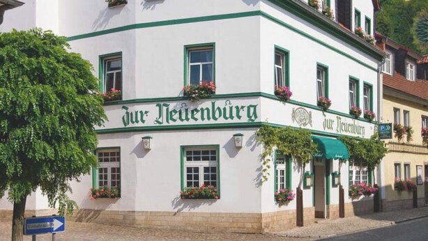A traditional building with a sign reading "Jura Neuenburg" and a castle in the background. - Pension Zur Neuenburg (Freyburg)