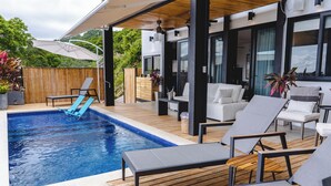 A pool area with lounge chairs, a wooden deck, and a modern outdoor seating area. - Ocean View Private Studio, Le Suite Santa Teresa (Provincia de Puntarenas)