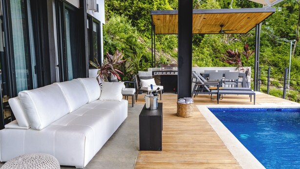 A modern outdoor living area with a white sofa, a grill, and a pool. - Ocean View Private Studio, Le Suite Santa Teresa (Provincia de Puntarenas)
