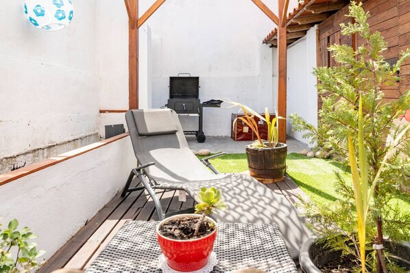 Relax in this serene outdoor space with a lounge chair, small table, and grill station.