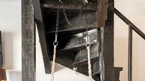 A macrame hanging chair with a cushion in a room with wooden floors and a staircase. - BBQ, Easy Parking & near Tejo, Lisbon Garden Stays (Lisboa)