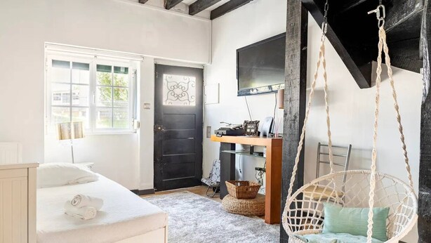 A room with a bed, a desk with a computer, a hanging chair, and a black door. - BBQ, Easy Parking & near Tejo, Lisbon Garden Stays (Lisboa)